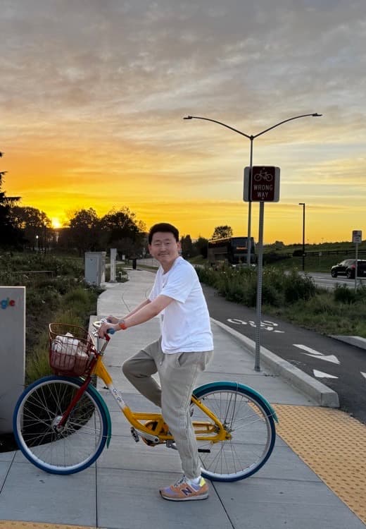 Yongman Kim riding a bicycle at sunset